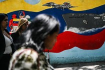 People walk past a mural of a Venezuelan warship and warplane in Caracas.