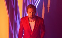 Ryan Gosling in a red suit in front of a vibrant background in "The Gray Man"