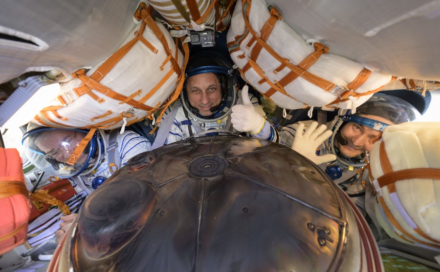 Three astronauts are crowded into a small capsule.