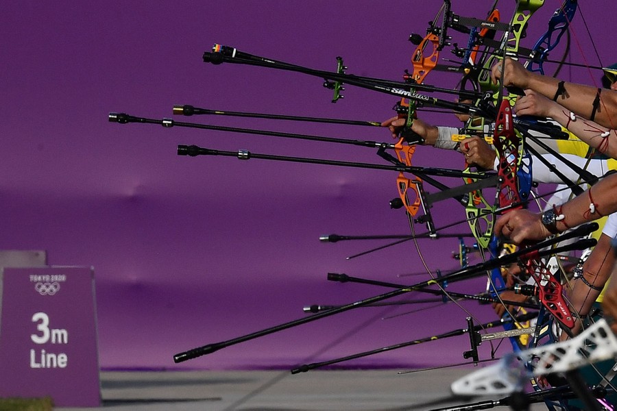 Several archers hold up their complex bows.