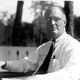 A black-and-white photo of Franklin D. Roosevelt, sitting in a chair and looking at the camera