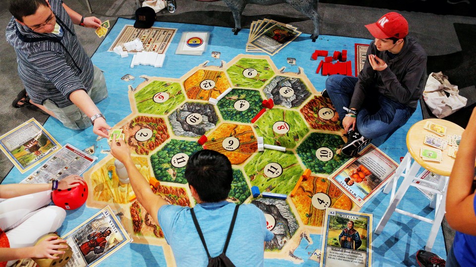 Three young men play the German board game Settlers of Catan