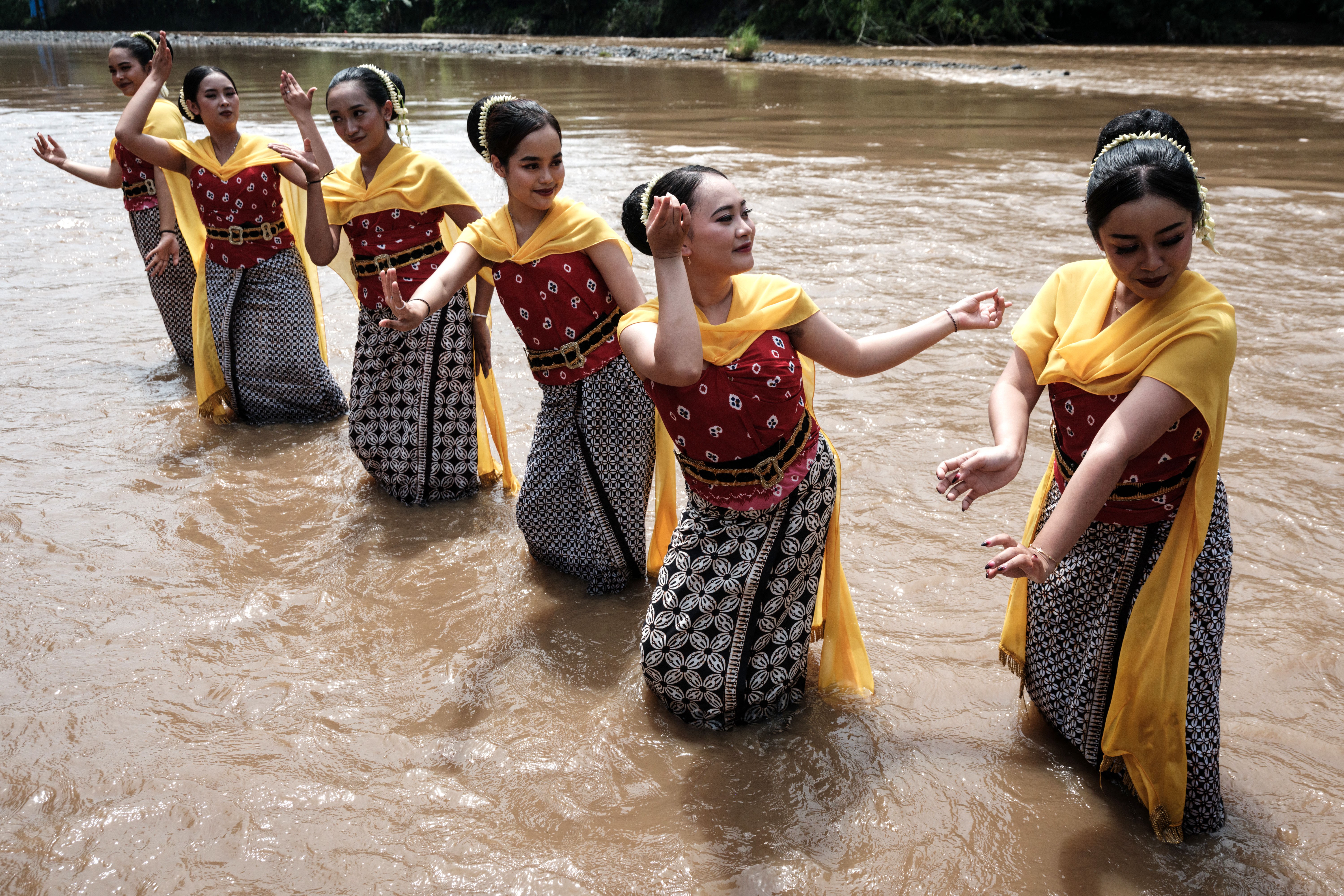 Six dancers perform in a shallow river.