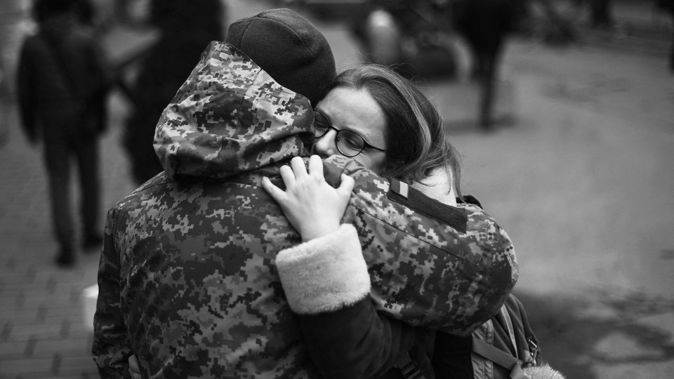 A Ukrainian soldier hugs his partner next to a military base where residents are queuing to join the army in Lviv.