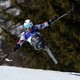 A seated skier catches some air during a fast downhill run, their arms outstretched.