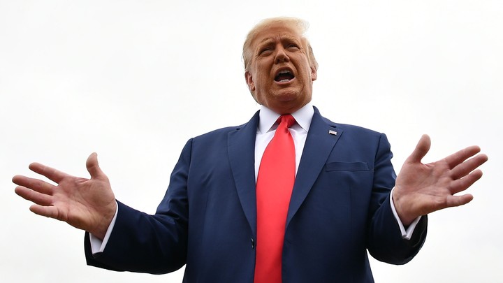 President Donald Trump speaking in a navy suit and red tie