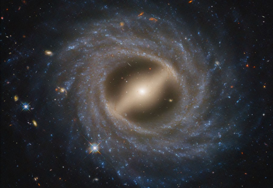 A view of a barred spiral galaxy with stars and other galaxies in the background