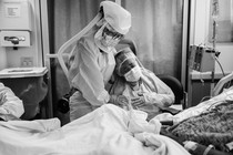 Romelia Navarro is comforted by Michele Younkin, a nurse, while sitting at the bedside of her dying husband.