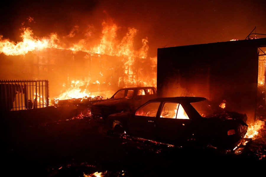 Several vehicles and buildings burn.