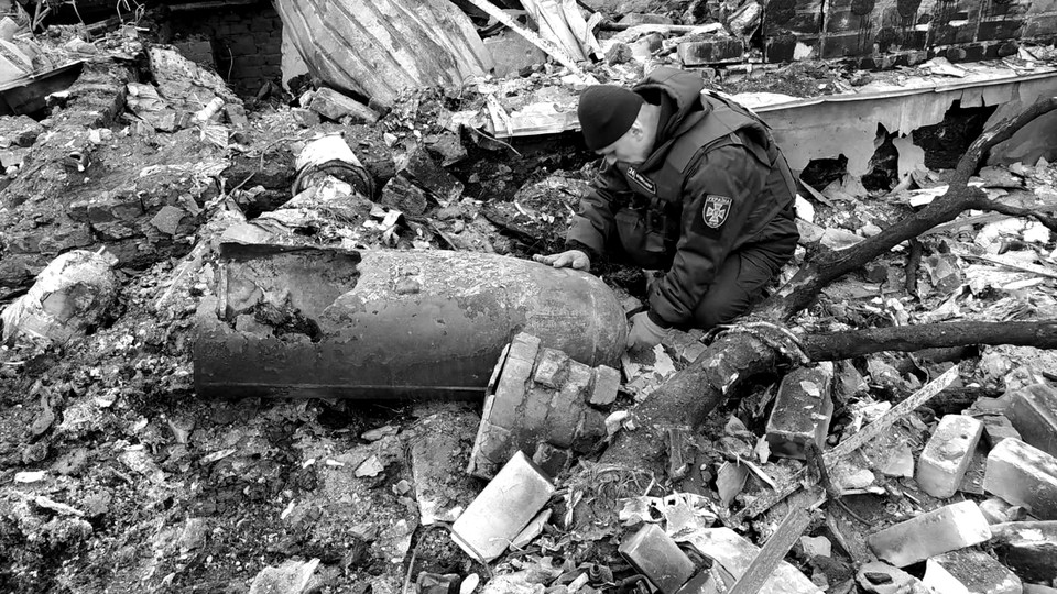 A man crouches next to unexploded ordnance in Ukraine.