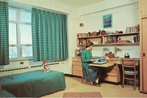 A drawing of a young woman sitting alone in a dorm room, on a typewriter