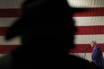 Trump speaking in front of a shadow over the American flag