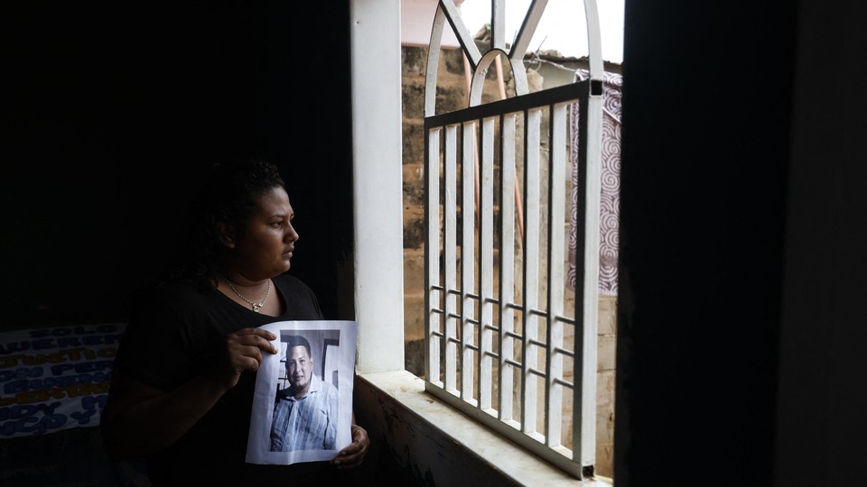 Photo of a woman staring out of a window while holding a photo of a man