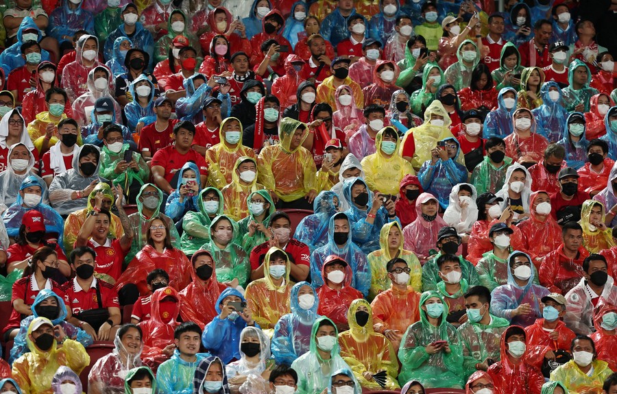 A sports-stadium seating area is filed with fans wearing different colored plastic rain ponchos.