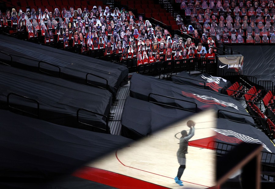 Cardboard cutouts of fans line bleachers as a basketball player is seen warming up before a game.