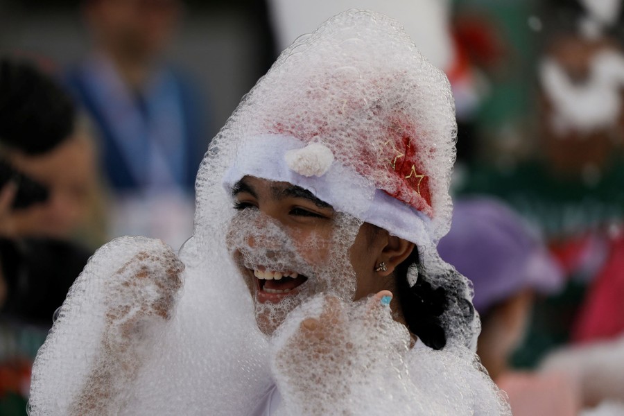 A girl wearing a Santa Claus hat plays in foam.