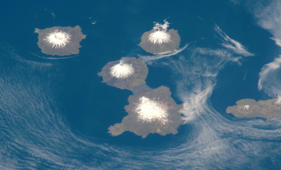 An overhead view of four volcanic peaks on three small islands.