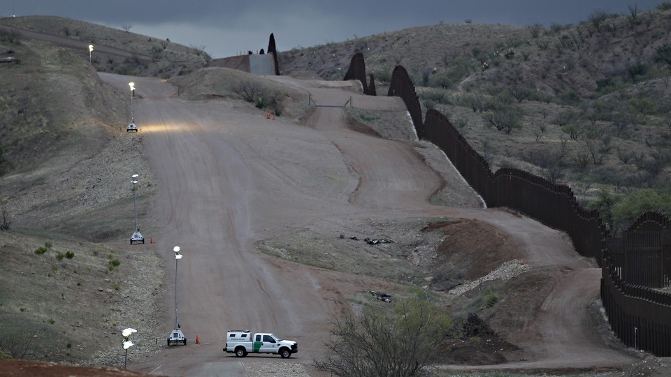 Customs and Border Patrol agent patrols along the international border after sunset in Nogales, Ariz.