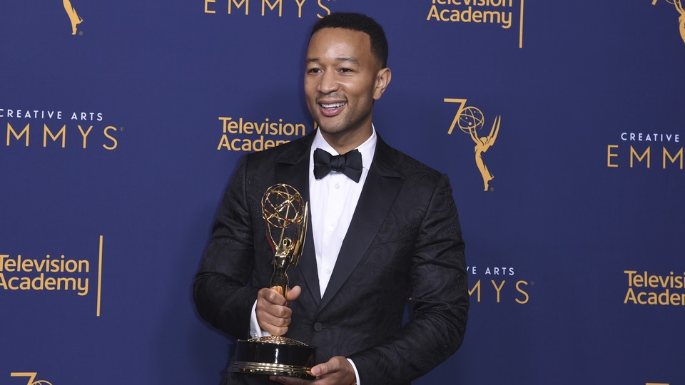 John Legend holding his Emmy award