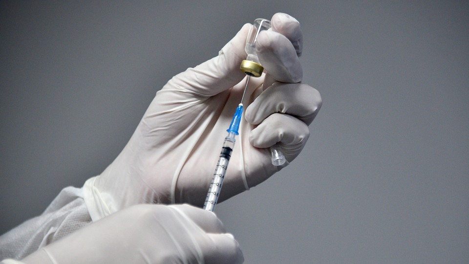 Hand wearing a medical glove holding a vaccine