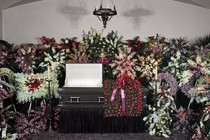 A casket at a funeral surrounded by flowers