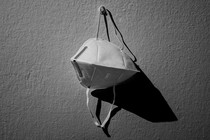 An image of a kn95 mask hanging on a hook against a white wall