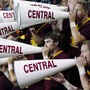 People hold megaphones that read "CENTRAL" along the side in the stands of a football game.