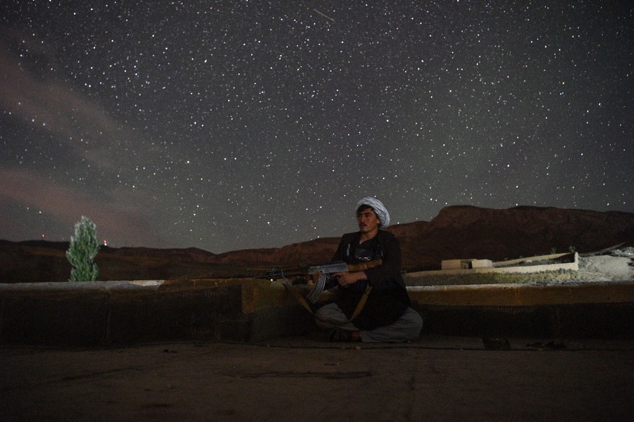A militia fighter sits under the stars, holding his weapon.