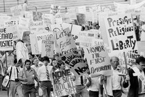 A black-and-white photo of a Reagan-era protest in front of the Supreme Court's steps, with signs reading "Preserve religious liberty" and "Honor the First Amendment"