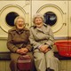 Two older women smiling and posing at a laundromat