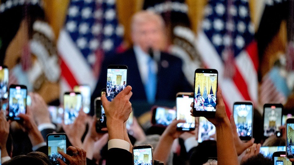 Donald Trump in the background, with phones recording him