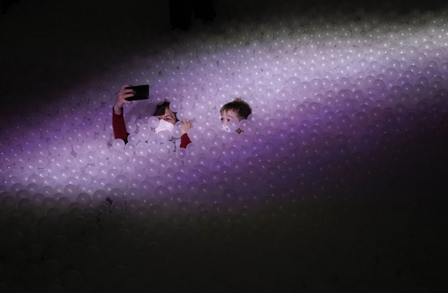 Two people buried in thousands of small plastic balls take a selfie.