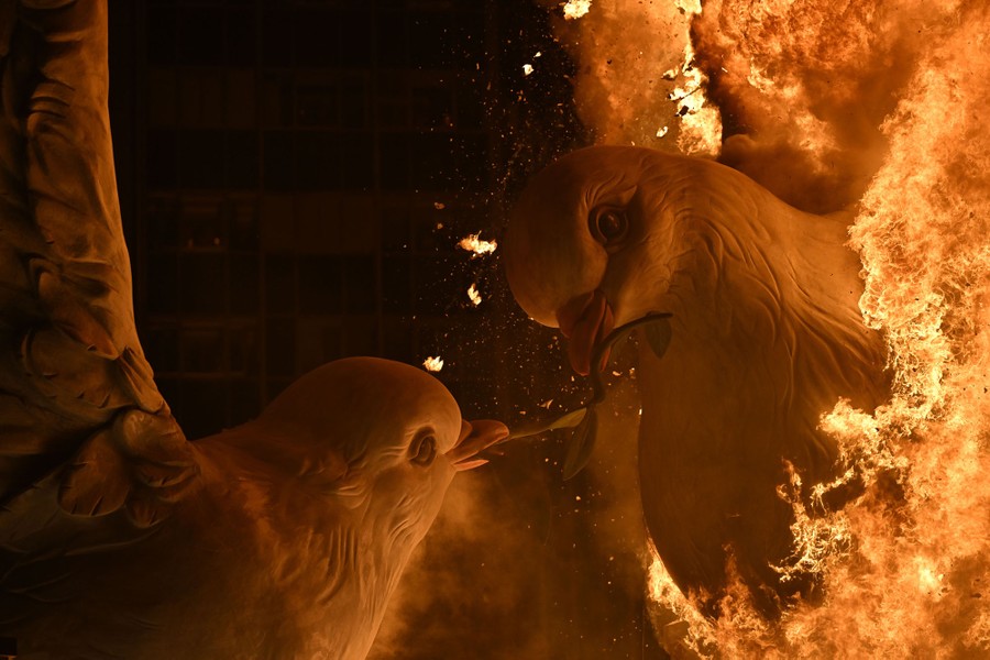 Two large sculptures of doves are consumed by flames.