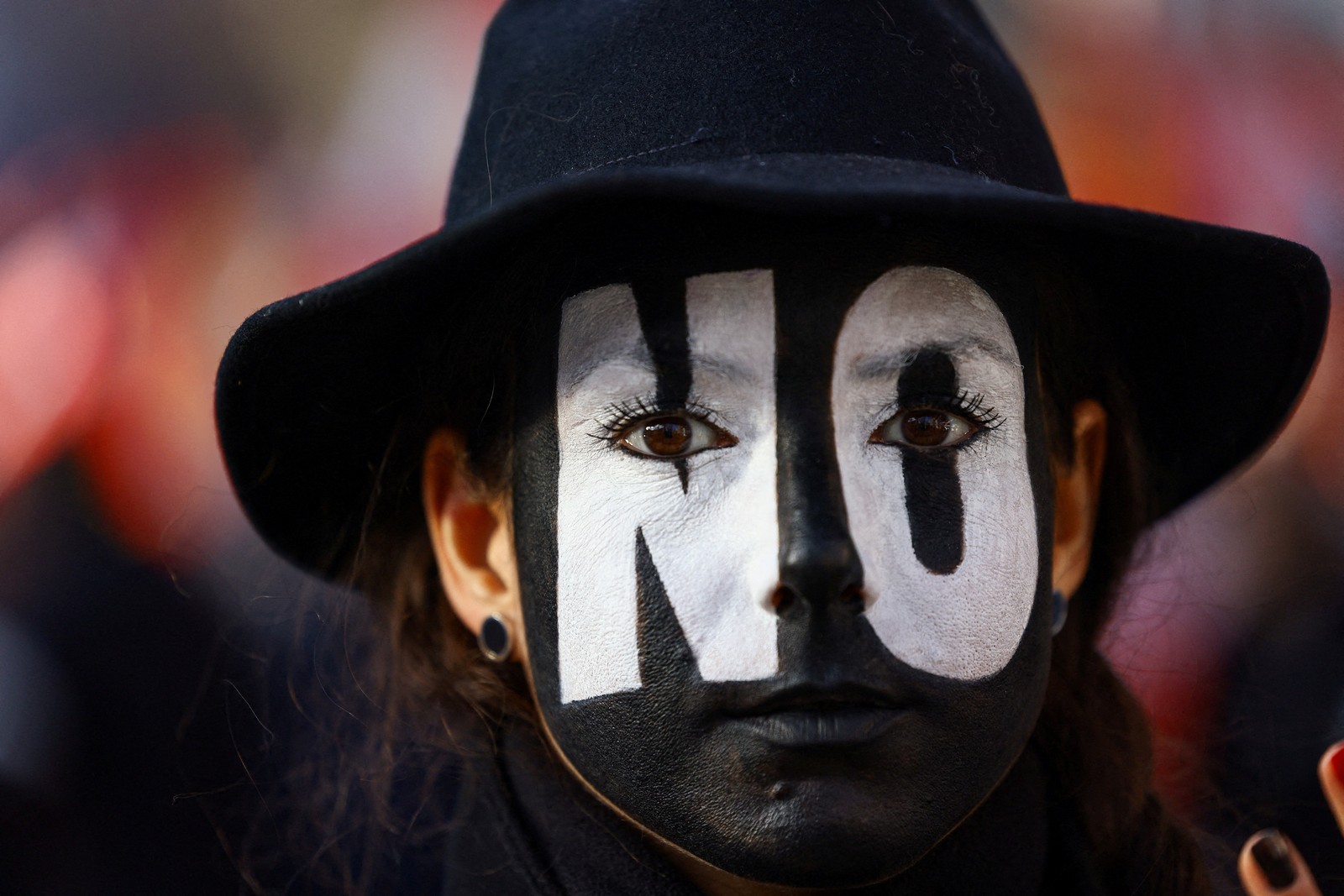 A demonstrator with the word 'No' painted across their face