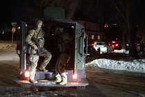 Masked and armed federal immigration officers in a vehicle at night with snow and ice on the street