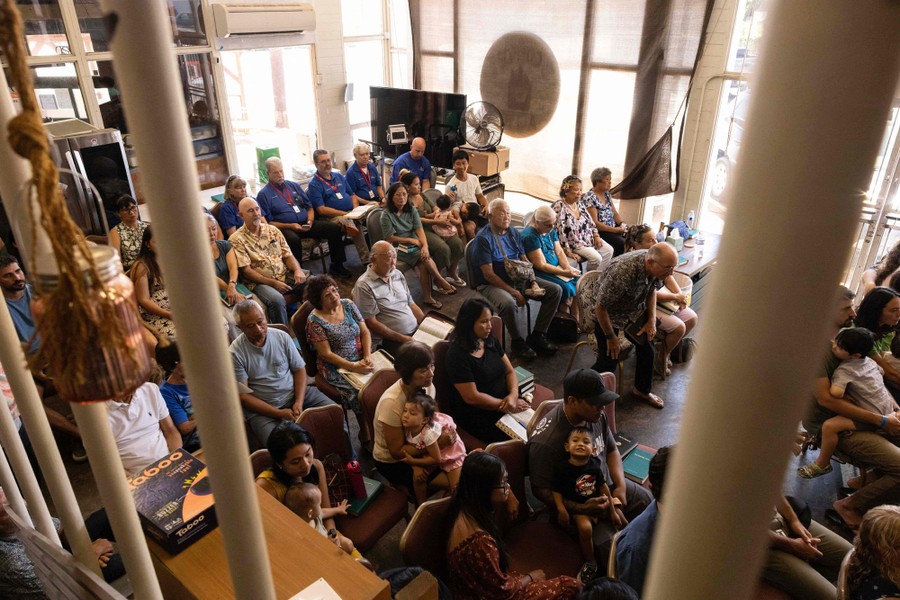 People sit in rows of chairs inside a coffee shop.