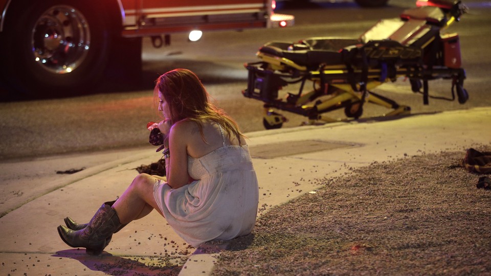 A young woman sits on a curb in Las Vegas, with an EMS vehicle behind her