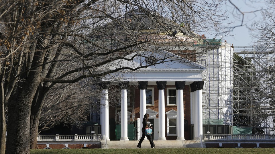 A woman walks past a building on the University of Virginia campus.