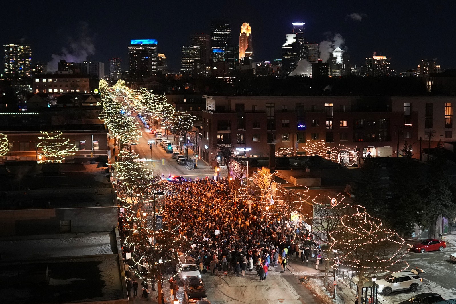 An elevated view of people standing together in a street at night, during a vigil