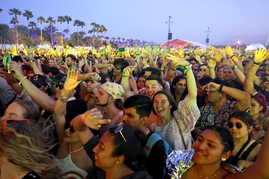 Audience members raise their arms while watching a performance.