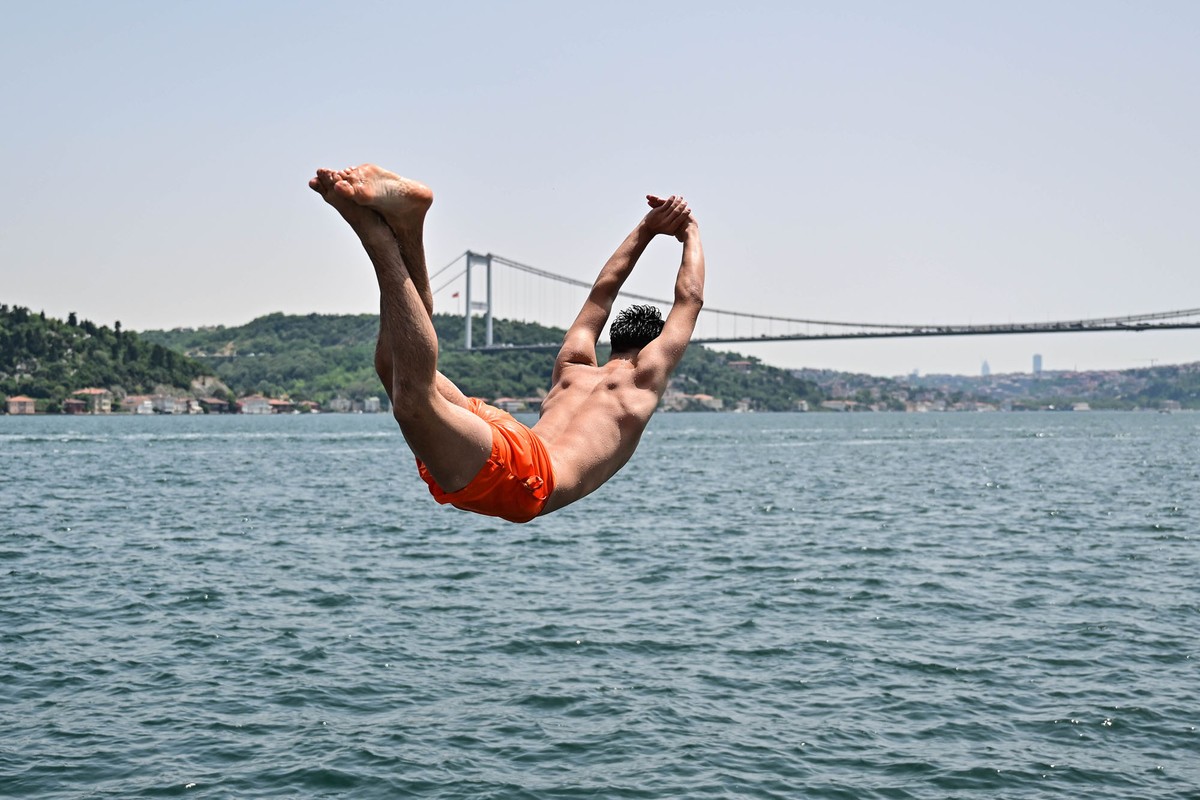 A person is seen mid-dive, falling toward a large body of water.