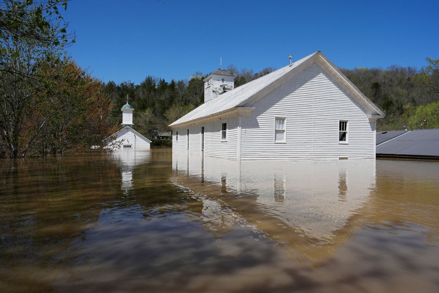 Two white wooden churches stand in muddy floodwater.