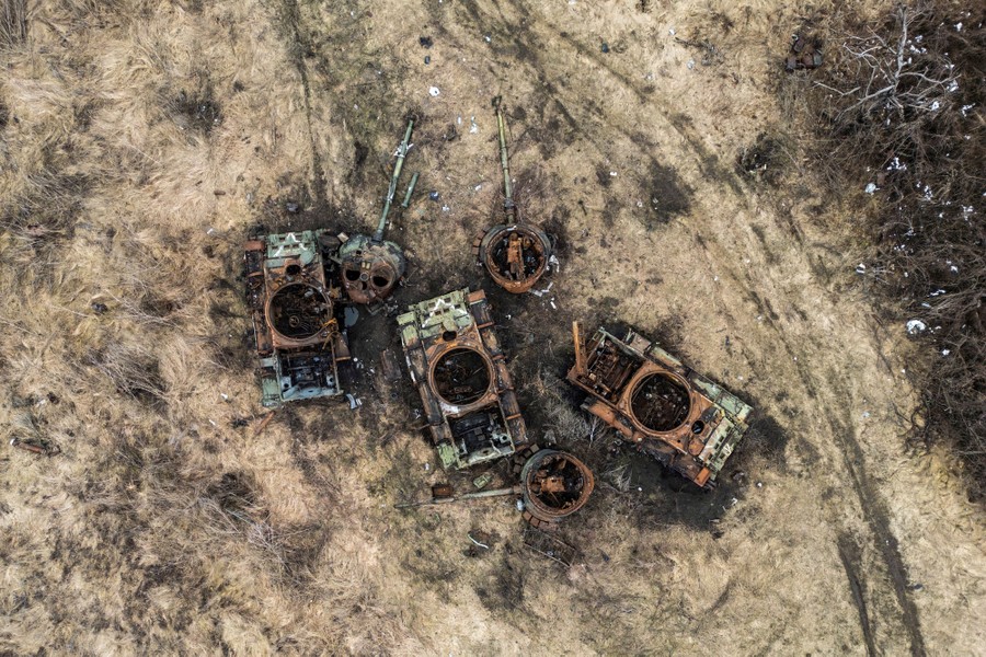 An aerial view of several destroyed military tanks, each of their turrets blown off and lying on the ground