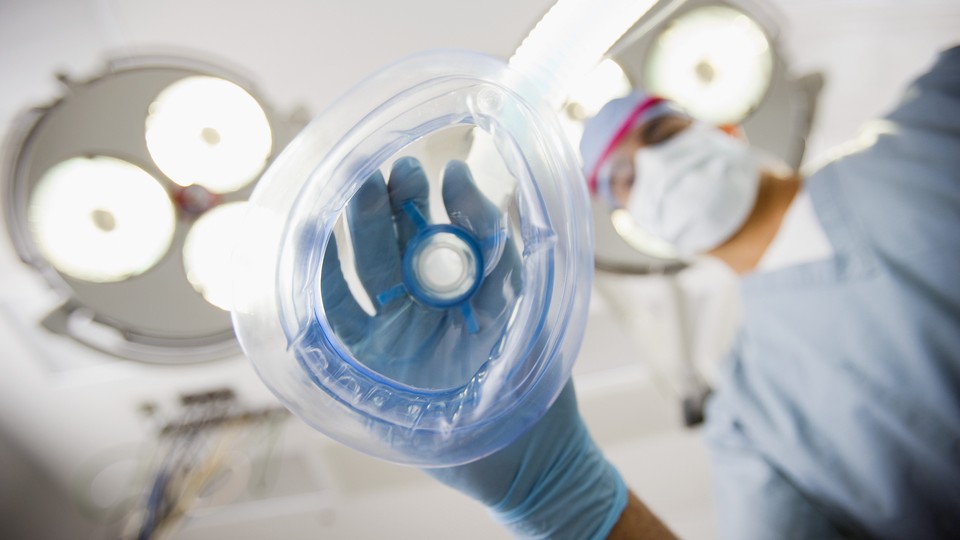 An anesthesiologist holds a mask toward the viewer