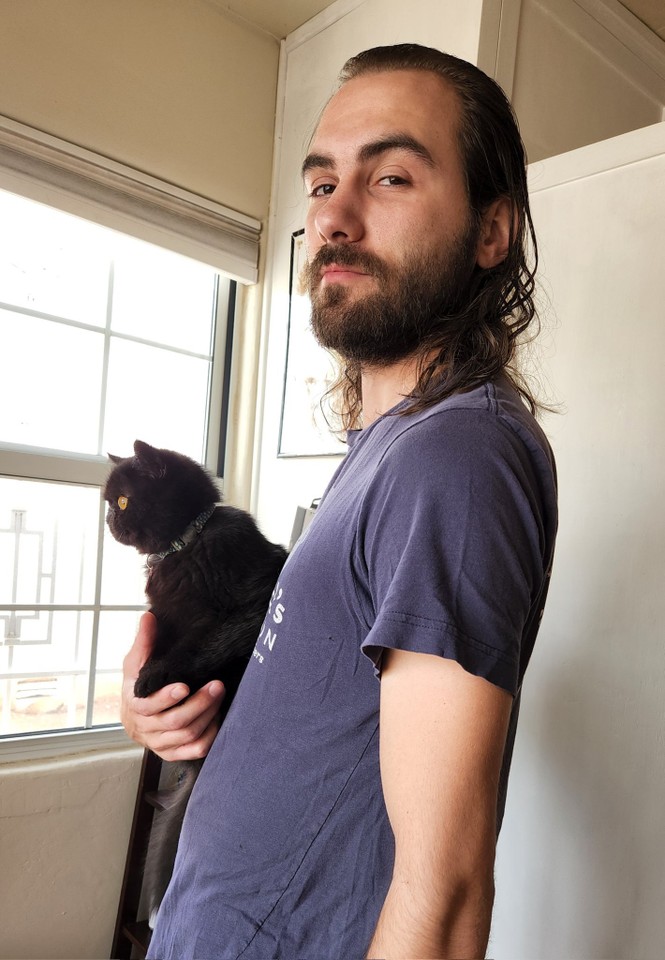 a man holding a black cat in his right arm