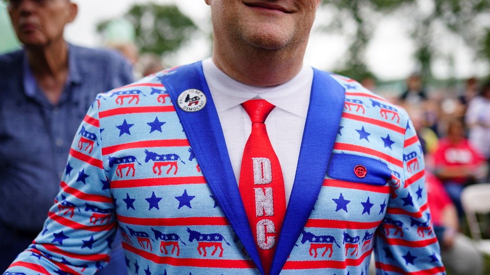 A smiling man is seen wearing a blazer featuring donkeys and a DNC tie
