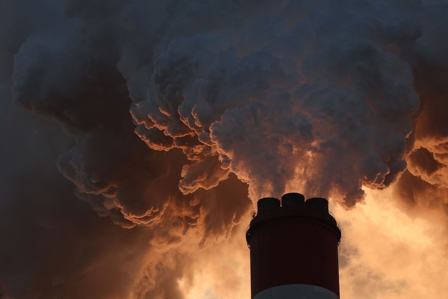 Smoke and steam billow from a tall industrial smokestack.