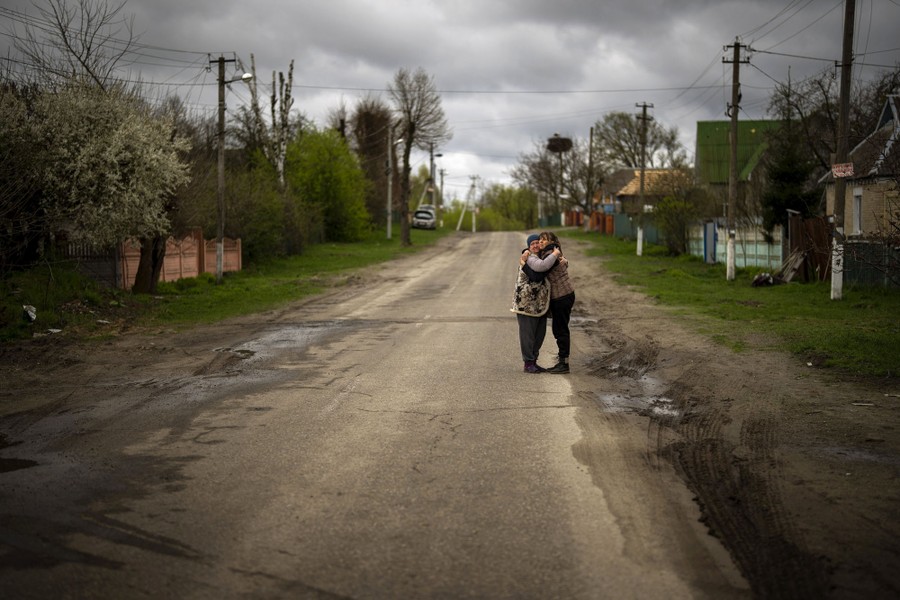 Two women embrace each other on an empty road.