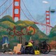 A homeless person in front of a mural in San Francisco