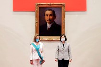Nancy Pelosi, wearing a white pantsuit with a turquoise sash, standing with Taiwan’s president in front of a painting of Sun Yat-sen